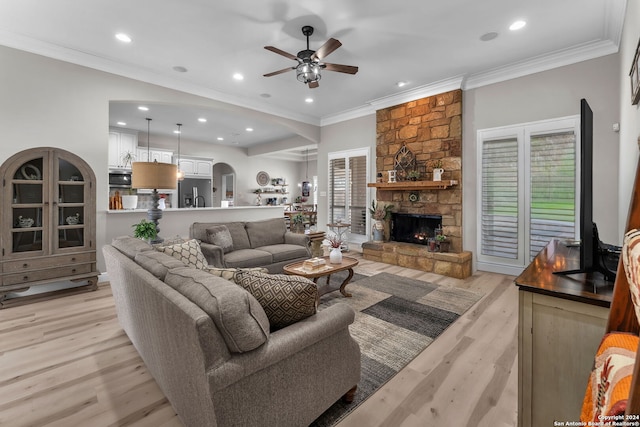 living room featuring ceiling fan, crown molding, light wood-type flooring, and a fireplace