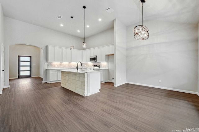 kitchen featuring an island with sink, white cabinets, and hanging light fixtures