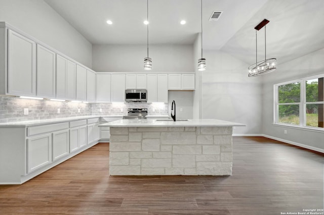 kitchen with pendant lighting, a kitchen island with sink, white cabinets, sink, and stainless steel appliances