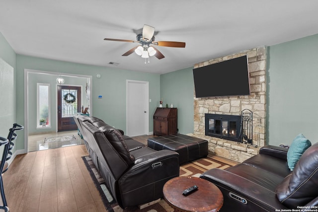 living room featuring ceiling fan, light hardwood / wood-style floors, and a fireplace