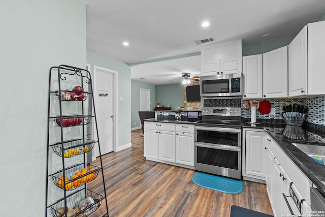 kitchen featuring dark wood-type flooring, tasteful backsplash, dark stone countertops, white cabinets, and appliances with stainless steel finishes