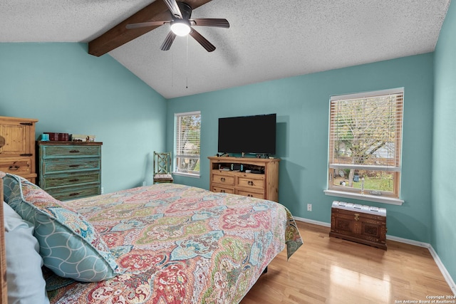 bedroom with a textured ceiling, lofted ceiling with beams, light hardwood / wood-style floors, and ceiling fan