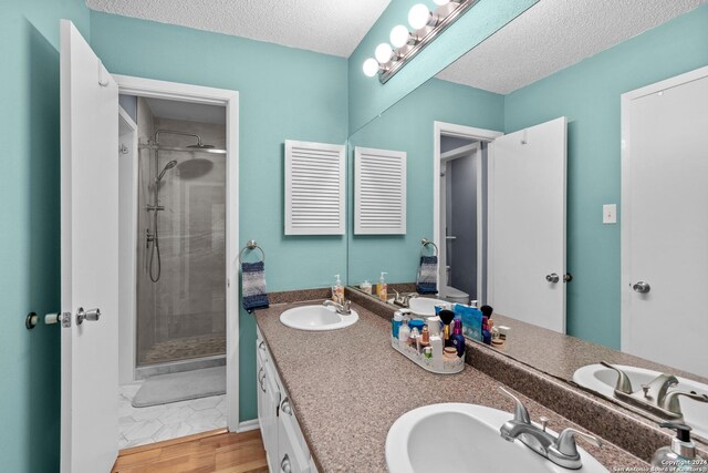 bathroom featuring vanity, an enclosed shower, a textured ceiling, and wood-type flooring