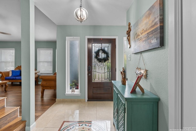 tiled foyer entrance featuring a notable chandelier