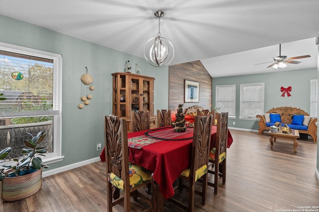 dining room featuring plenty of natural light, wood-type flooring, ceiling fan with notable chandelier, and lofted ceiling