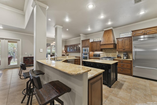 kitchen featuring a breakfast bar, sink, built in appliances, custom range hood, and kitchen peninsula