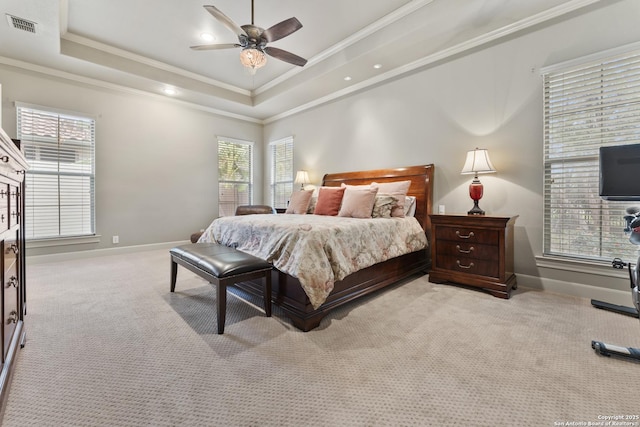 carpeted bedroom with ceiling fan, multiple windows, and a tray ceiling