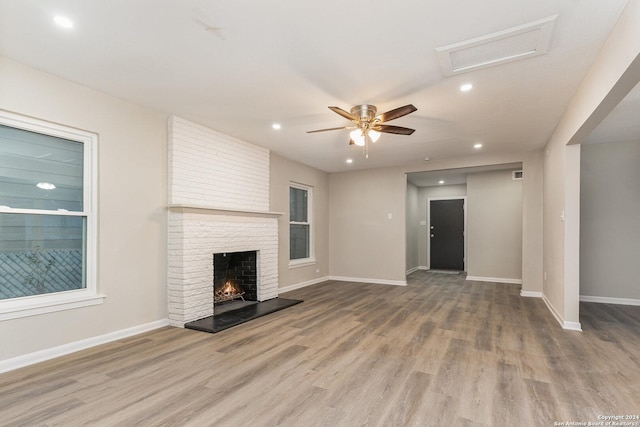 unfurnished living room with ceiling fan, light wood-type flooring, and a brick fireplace