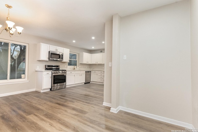 kitchen featuring appliances with stainless steel finishes, decorative light fixtures, white cabinetry, and sink