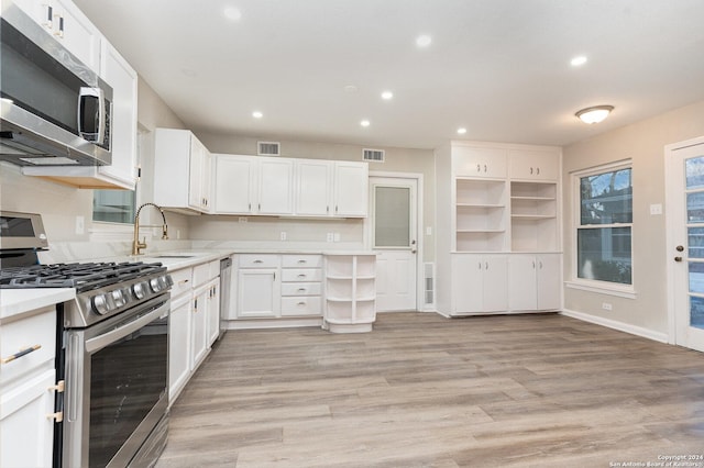 kitchen with appliances with stainless steel finishes, light wood-type flooring, white cabinetry, and sink