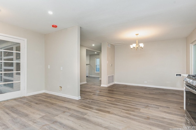 spare room with a chandelier and hardwood / wood-style flooring