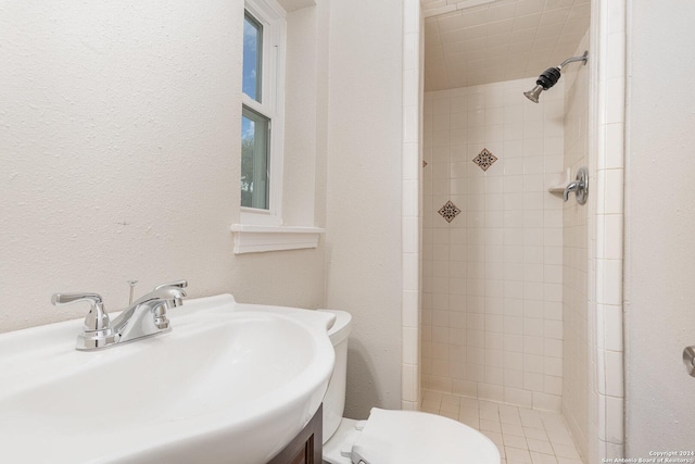 bathroom with tiled shower, toilet, and sink