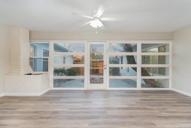 empty room featuring light hardwood / wood-style floors, ornate columns, and a wealth of natural light