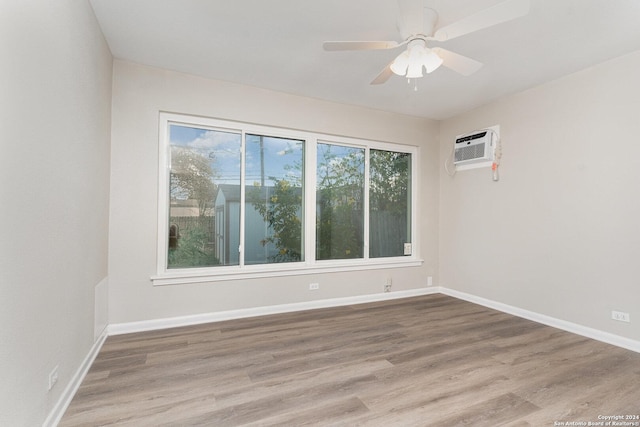 unfurnished room featuring wood-type flooring, an AC wall unit, and ceiling fan