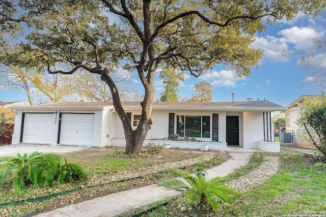 single story home with cooling unit and a garage