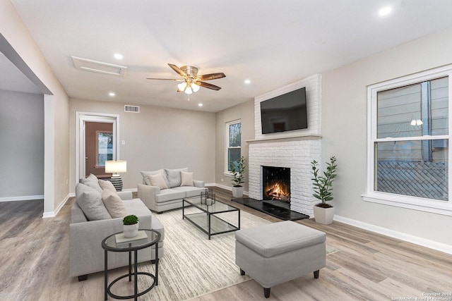 living room featuring hardwood / wood-style floors, ceiling fan, and a fireplace