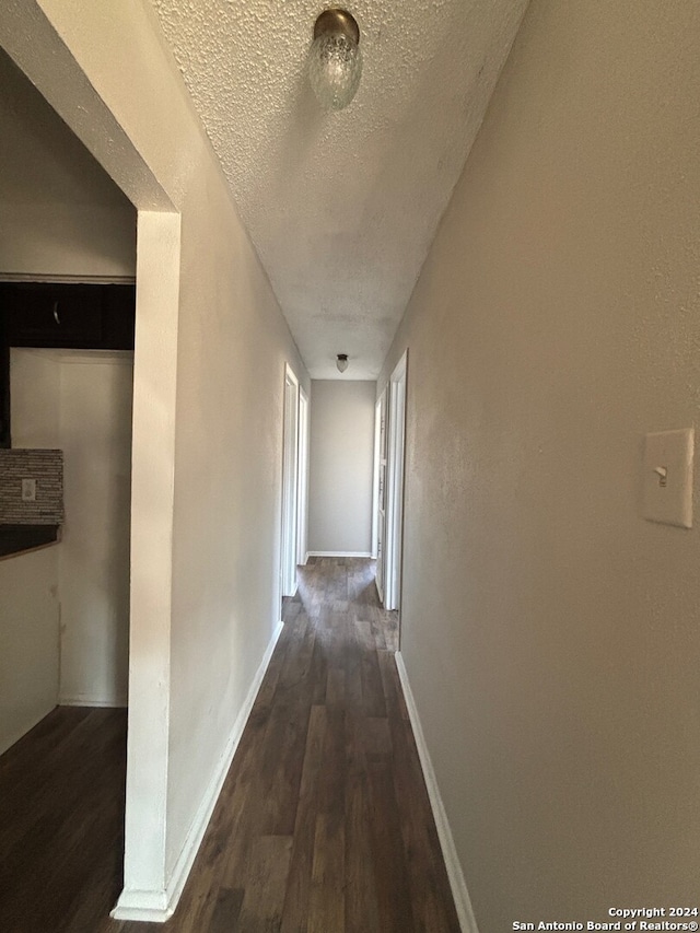 hall featuring dark hardwood / wood-style flooring and a textured ceiling