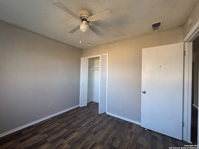 unfurnished bedroom with ceiling fan, a closet, dark wood-type flooring, and a textured ceiling