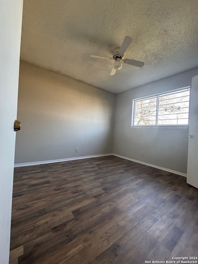 spare room with a textured ceiling, ceiling fan, and dark hardwood / wood-style floors