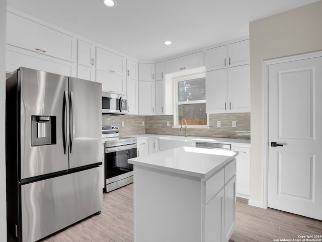 kitchen with white cabinetry, a center island, sink, backsplash, and appliances with stainless steel finishes