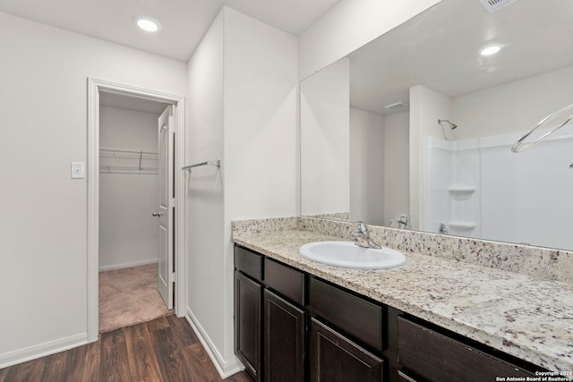 bathroom with hardwood / wood-style flooring, vanity, and walk in shower