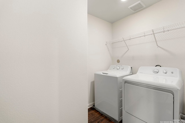 clothes washing area featuring dark hardwood / wood-style flooring and washer and dryer