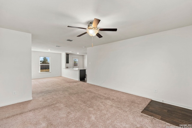 unfurnished living room featuring ceiling fan and light colored carpet