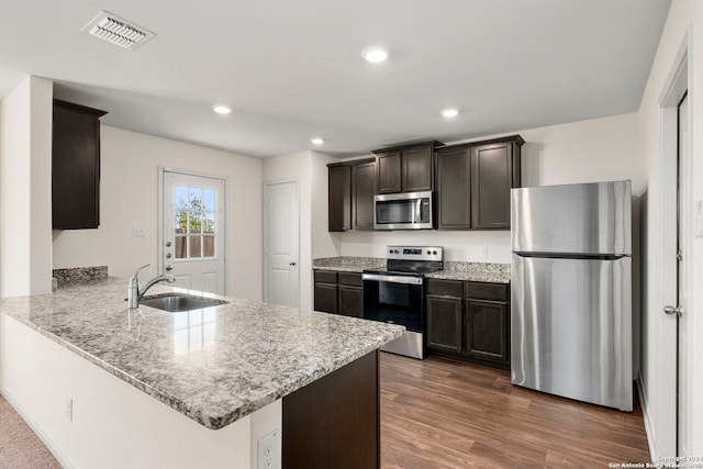 kitchen featuring sink, stainless steel appliances, dark wood-type flooring, kitchen peninsula, and dark brown cabinets