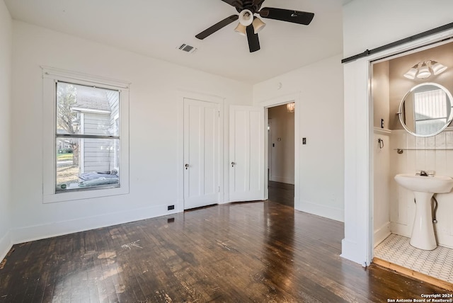 unfurnished bedroom with dark hardwood / wood-style floors, ceiling fan, and connected bathroom