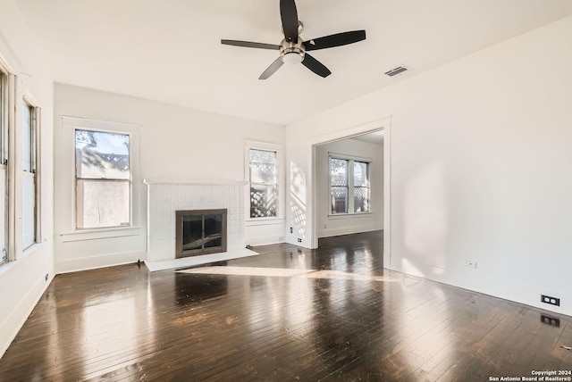 unfurnished living room featuring ceiling fan, plenty of natural light, dark wood-type flooring, and a brick fireplace