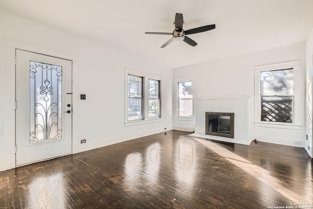 unfurnished living room with ceiling fan, dark hardwood / wood-style flooring, and a brick fireplace