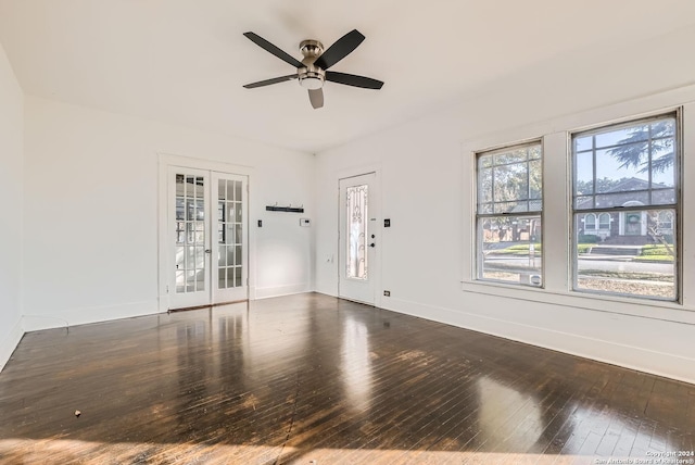 empty room with ceiling fan, dark hardwood / wood-style flooring, and french doors