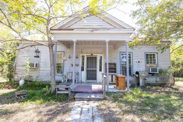 neoclassical / greek revival house featuring a porch and cooling unit