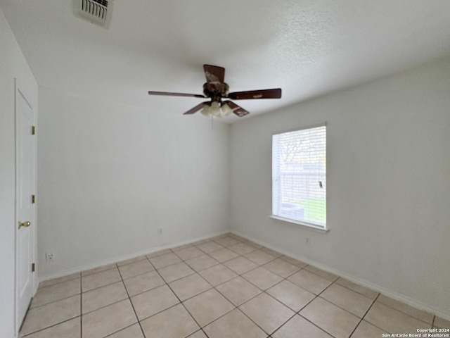 tiled spare room with ceiling fan