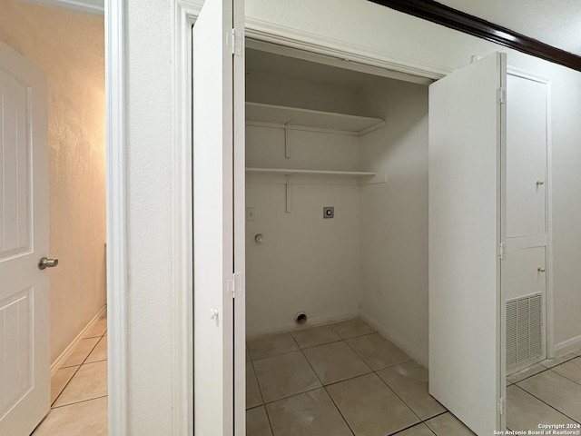 laundry room with electric dryer hookup, hookup for a washing machine, light tile patterned floors, and ornamental molding