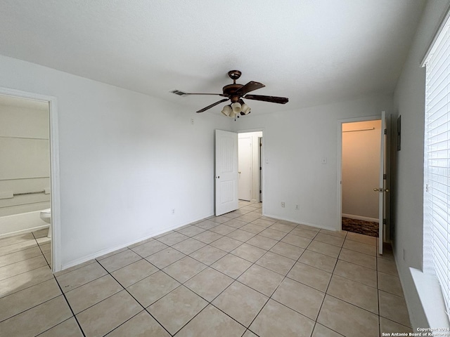 unfurnished bedroom featuring light tile patterned floors, connected bathroom, and ceiling fan