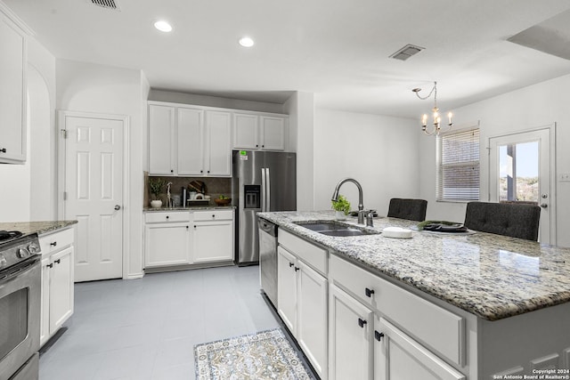 kitchen with a notable chandelier, sink, white cabinetry, appliances with stainless steel finishes, and an island with sink