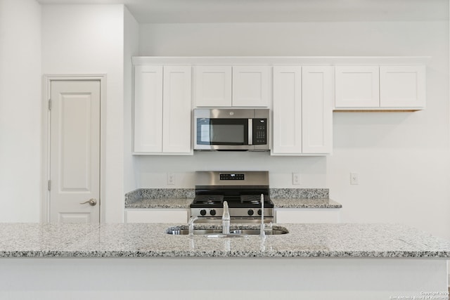 kitchen featuring white cabinetry, appliances with stainless steel finishes, and light stone counters