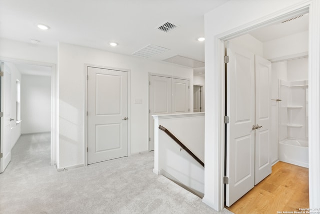 hallway with light colored carpet, visible vents, an upstairs landing, and recessed lighting