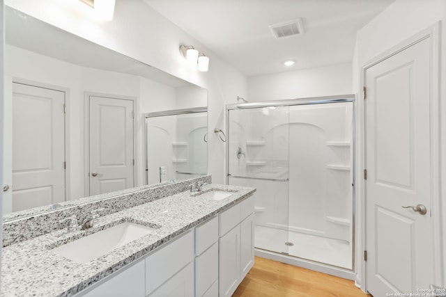 bathroom featuring a shower stall, wood finished floors, a sink, and visible vents