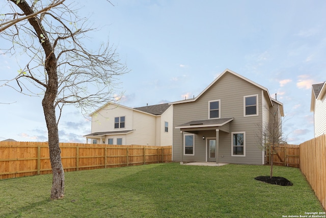 back of property featuring a yard, a fenced backyard, and a patio area