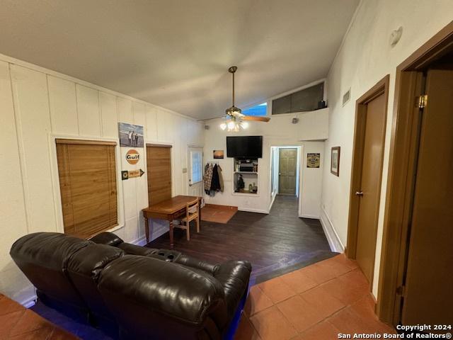 living room featuring tile patterned floors, ceiling fan, and vaulted ceiling