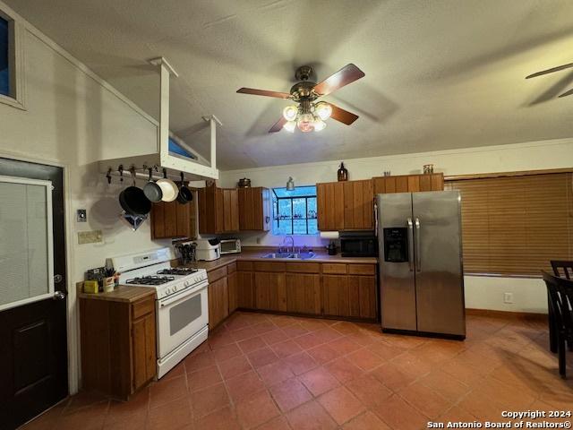 kitchen featuring sink, stainless steel refrigerator with ice dispenser, vaulted ceiling, ceiling fan, and gas range gas stove