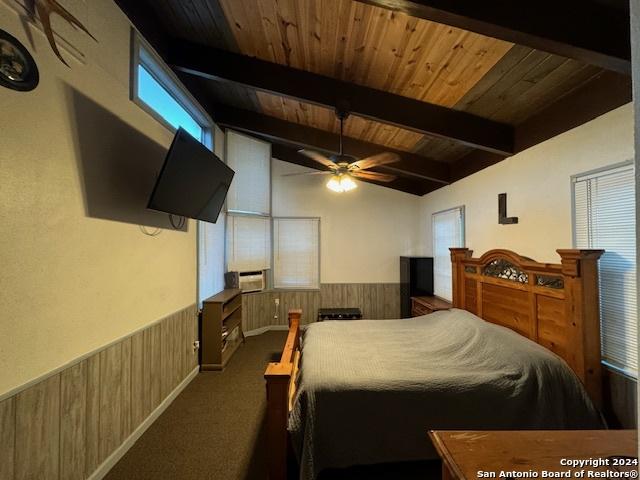 bedroom featuring beamed ceiling, wood walls, and wood ceiling