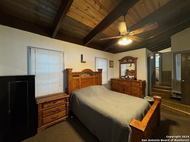 carpeted bedroom featuring lofted ceiling with beams, ceiling fan, and wood ceiling