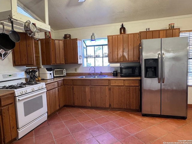 kitchen featuring tile patterned flooring, sink, white range with gas stovetop, and stainless steel refrigerator with ice dispenser