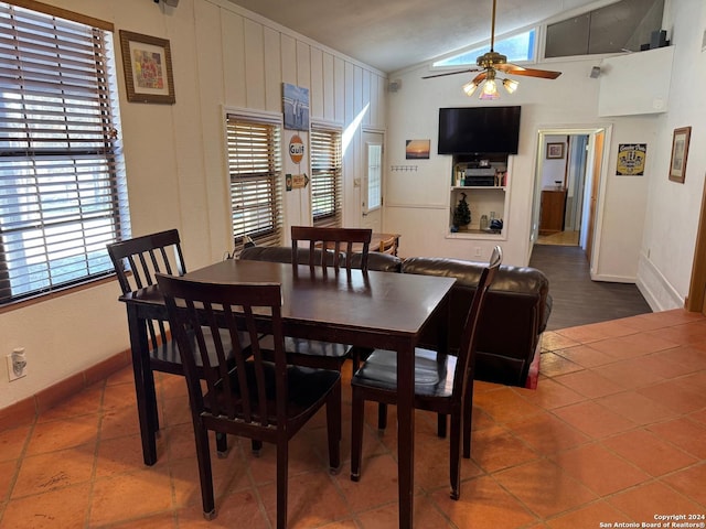 dining space featuring ceiling fan, dark tile patterned floors, and lofted ceiling