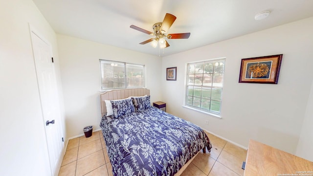 bedroom featuring ceiling fan, light tile patterned floors, and multiple windows