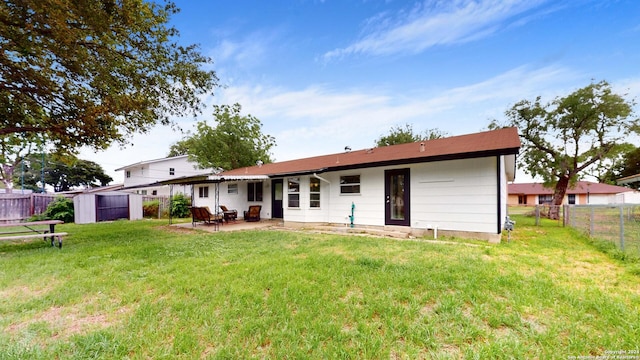 back of house featuring a storage shed, a patio area, and a lawn