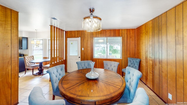 tiled dining area featuring a notable chandelier and wood walls